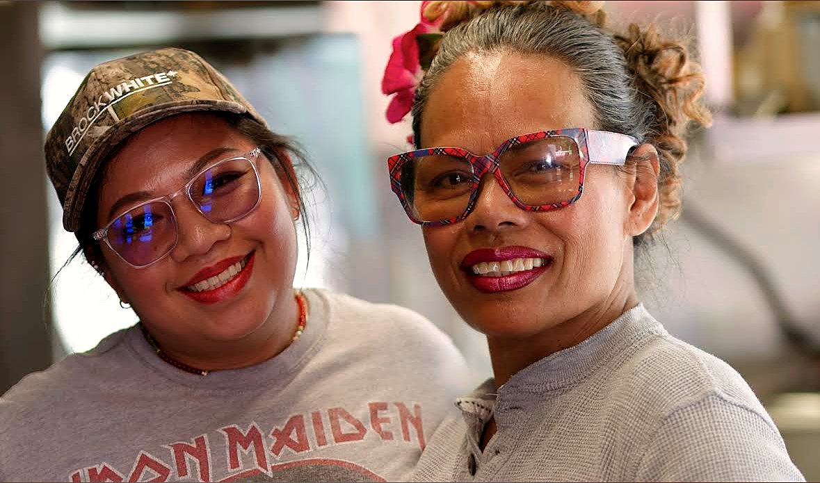 The two women behind Super Thai smiling together inside the truck
