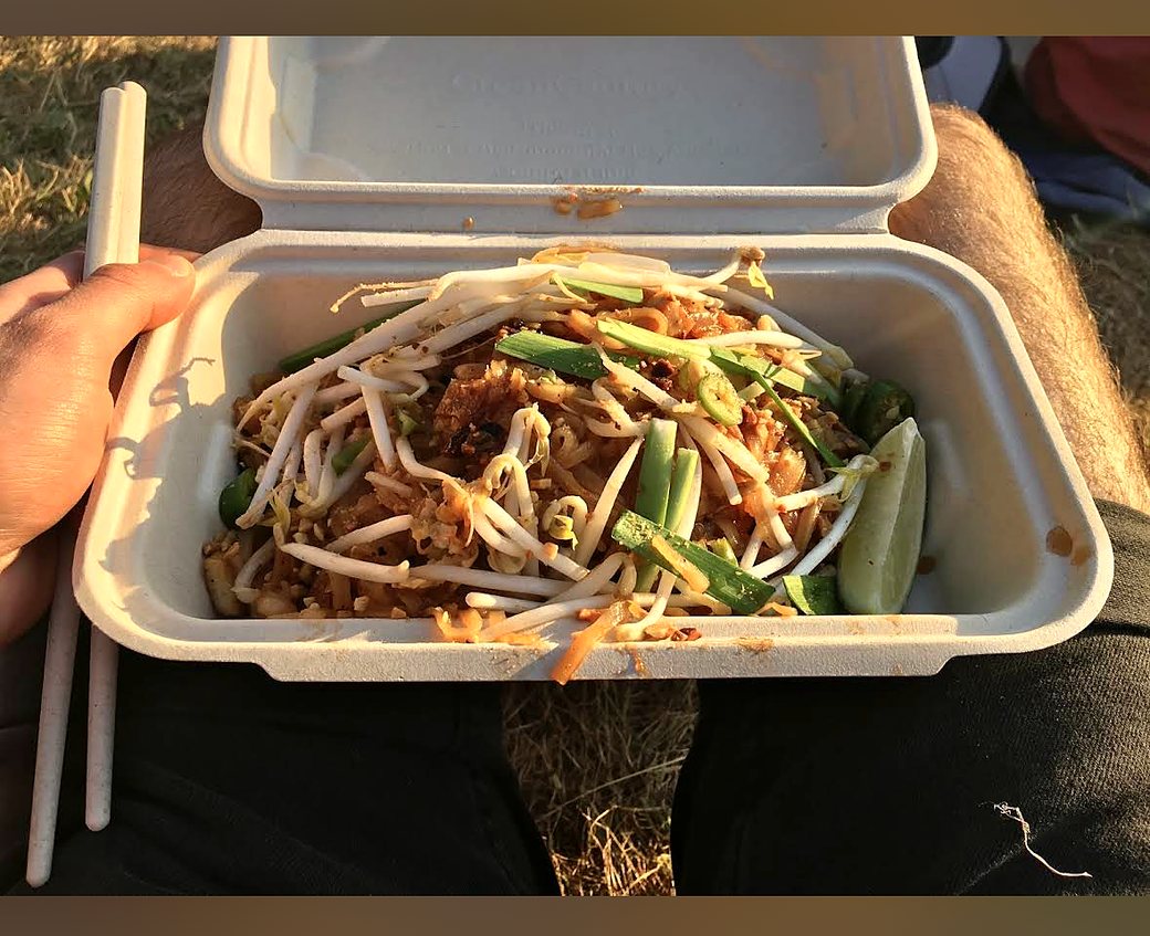 Pad Thai held with chopsticks in warm sunset light